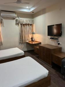 a bedroom with two beds and a flat screen tv at Hotel Ken in Rānchī