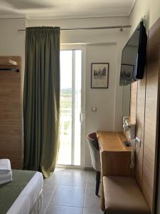 um quarto de hotel com uma cama, uma secretária e uma janela em Perea Hotel em Perea