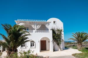 a white house with palm trees and a blue sky at Oia Sunset Luxury Villa in Oia