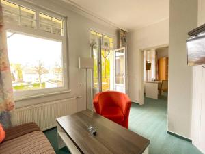 Habitación con silla roja, mesa y ventana en Strandhotel Graal-Müritz, en Graal-Müritz