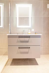 a bathroom with a white sink and a mirror at Gjermesøy Luxury Apartment in Ballstad
