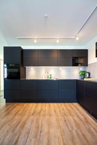 a large kitchen with black cabinets and wooden floors at Gjermesøy Luxury Apartment in Ballstad