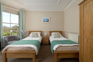 two beds in a room with a window at Epchris House in Ilfracombe