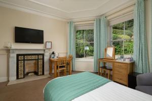 a bedroom with a bed and a fireplace and a television at Epchris House in Ilfracombe