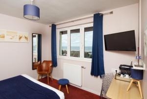 a bedroom with a bed and a tv and windows at Saint Aubin Logis Hôtel & Restaurant in Saint-Aubin-sur-Mer