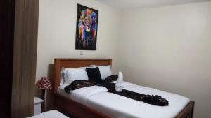 1 dormitorio con 1 cama con sábanas blancas y una pintura en Lacasa accommodation, en Naivasha