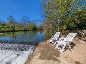 two white chairs sitting next to a river at Art Room & Apartment in Ogulin