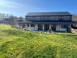 una casa en una colina con un campo verde en The Pier House en Lochgilphead