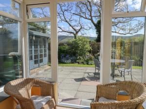 a screened in porch with chairs and a table at 24 Dolithel in Tywyn