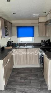 cocina con fregadero y ventana azul en Luxury Caravan in Towyn North Wales, en Abergele