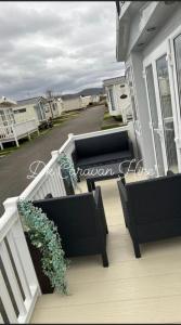 un porche con 2 sillas y una planta en una casa en Luxury Caravan in Towyn North Wales, en Abergele