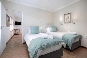 - 2 lits dans une chambre blanche et bleue dans l'établissement Steenbok House self catering Apartment, à Hermanus