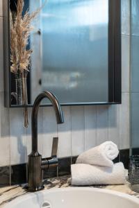 ein Waschbecken mit einem Wasserhahn und Handtüchern auf der Theke in der Unterkunft Gentle Hide Designhotel in Salzburg