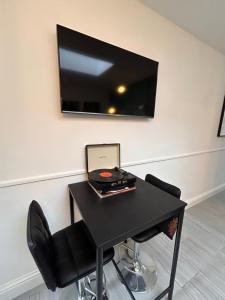 una mesa negra con ordenador portátil y TV en la pared en Vibrant Bungalow 2 Bedroom Flat with secure private parking, en Birmingham