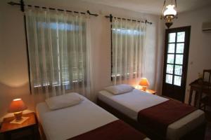 2 camas en una habitación con 2 lámparas y una ventana en Misafir Evi, en Kayakoy