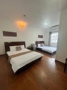 2 łóżka w pokoju z drewnianą podłogą w obiekcie Nhật Vân 2 w Ho Chi Minh