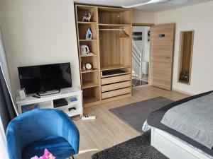 1 dormitorio con 1 cama, TV y silla azul en Chambre deluxe au 2ème étage, chambre double au 4ème étage PAS UN HÔTEL en Bruselas