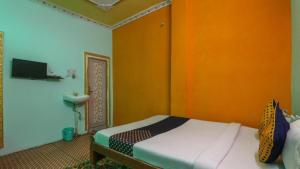 a bedroom with a bed with an orange wall at New Happy palace Inn Gaya Near By Mahabodhi Temple in Gaya