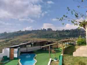 a resort with a swimming pool with a hill in the background at Qabuleka BnB in Nongoma