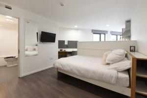 a white bedroom with a bed and a television at For Students Only Cosy Ensuite Rooms With Private Bathrooms at Dobbie's Point in Glasgow in Glasgow