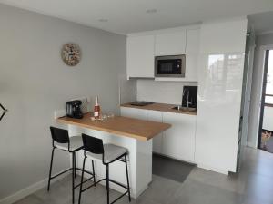 a kitchen with white cabinets and a counter with stools at Koka View in Playa del Ingles