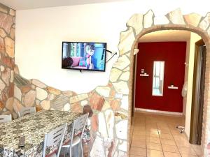 Habitación con pared de piedra y TV en la pared. en Appartamento Lavigna, en Marina di Camerota