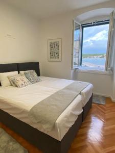 1 dormitorio con 1 cama grande y ventana grande en Beach House Tisno with Sea View, en Tisno