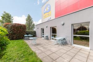 eine Terrasse außerhalb eines Gebäudes mit Tischen und Stühlen in der Unterkunft Ace Hotel Roanne in Mably