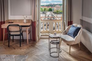 a living room with a table and a chair and a balcony at River Dance Suites by Adrez in Prague
