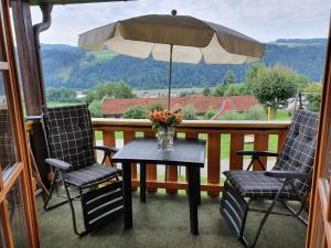una mesa y dos sillas y una sombrilla en un porche en Idyllische Ferienwohnung mit Blick auf die Donau - b48596, en Obernzell