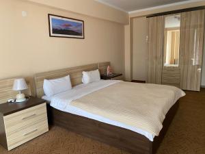 a hotel room with a large bed and a nightstand at Санаторий Казахстан in Gornyy Gigant