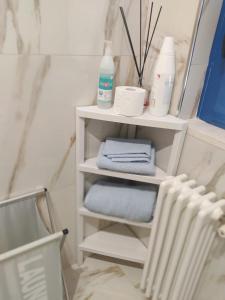 une étagère blanche avec des serviettes et un radiateur dans la salle de bains dans l'établissement Dimora OltreMare, à Bari