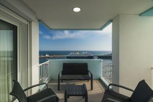 a balcony with a chair and a boat in the water at Ocean Vista - Premium CityCenter in Ponta Delgada