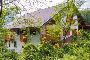 a white house with red windows and trees at Winterfell Hakuba in Hakuba