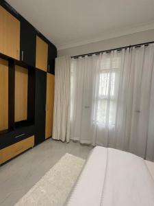 1 dormitorio con cama blanca y ventana en Mayvad Homes, en Kampala