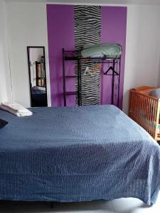 a bedroom with a blue bed and purple walls at Petite maison indépendante in Le Havre
