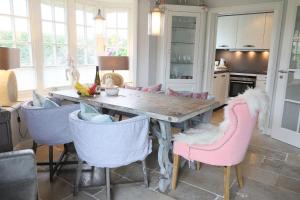 a kitchen with a wooden table and pink chairs at Osterweg-53c-DHH in Wenningstedt
