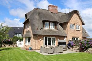 a large brick house with a thatched roof at Osterweg-53c-DHH in Wenningstedt