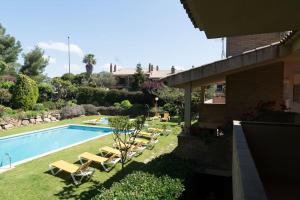 a swimming pool with lounge chairs next to a house at SeaHomes Vacations - CALA BANYS Apt in Lloret de Mar