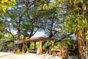 a wooden pavilion under a tree in a park at Ruenpakkiangnan เรือนพักเคียงน่าน in Phitsanulok