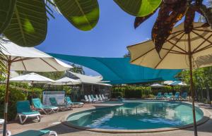 布魯姆的住宿－Broome Beach Resort - Cable Beach, Broome，一个带遮阳伞和躺椅的游泳池以及一个游泳池