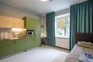 Habitación con armarios verdes y cocina con ventana en Solo Society Kaunas Apartments en Kaunas