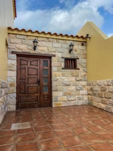 un edificio con una porta in legno e un muro di pietra di El Olivar Lidia a Puerto del Rosario