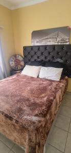 a bedroom with a large bed with a black headboard at Mandoland in Manzini