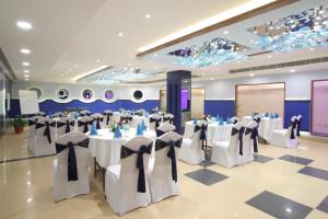 - une salle de banquet avec des tables et des chaises blanches dans l'établissement Hotel Adityaz, à Gwalior