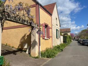 een gebouw met paarse bloemen aan de kant van een straat bij Sous la Glycine in Giverny