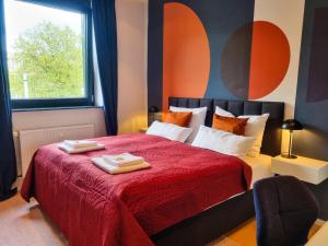um quarto com uma cama vermelha com duas toalhas em maremar - City Design Apartment - Luxus Boxspringbetten - Highspeed WIFI - Arbeitsplätze em Braunschweig