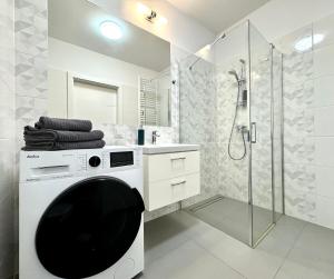 een witte badkamer met een douche en een wasmachine bij K22 Komputerowa 7 Chopin Airport in Warschau