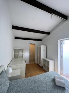 a white room with a bed and a refrigerator at Relógio Guest House in Porto