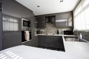 una cocina con armarios grises y fregadero en Modern 3-bedroom Retreat, en Swalwell